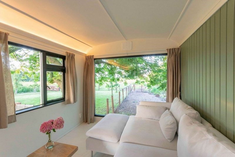 Een unieke salonwagen met panoramaraam dat uitkijkt over het weiland en varkens, geiten, schapen, kippen en eenden