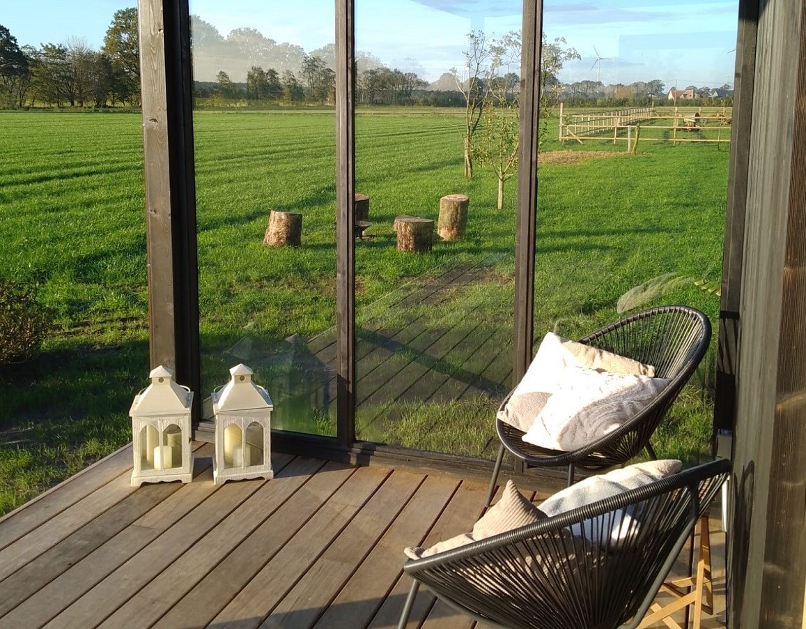 Tiny house met overdekt terras en een weids uitzicht over de weilanden