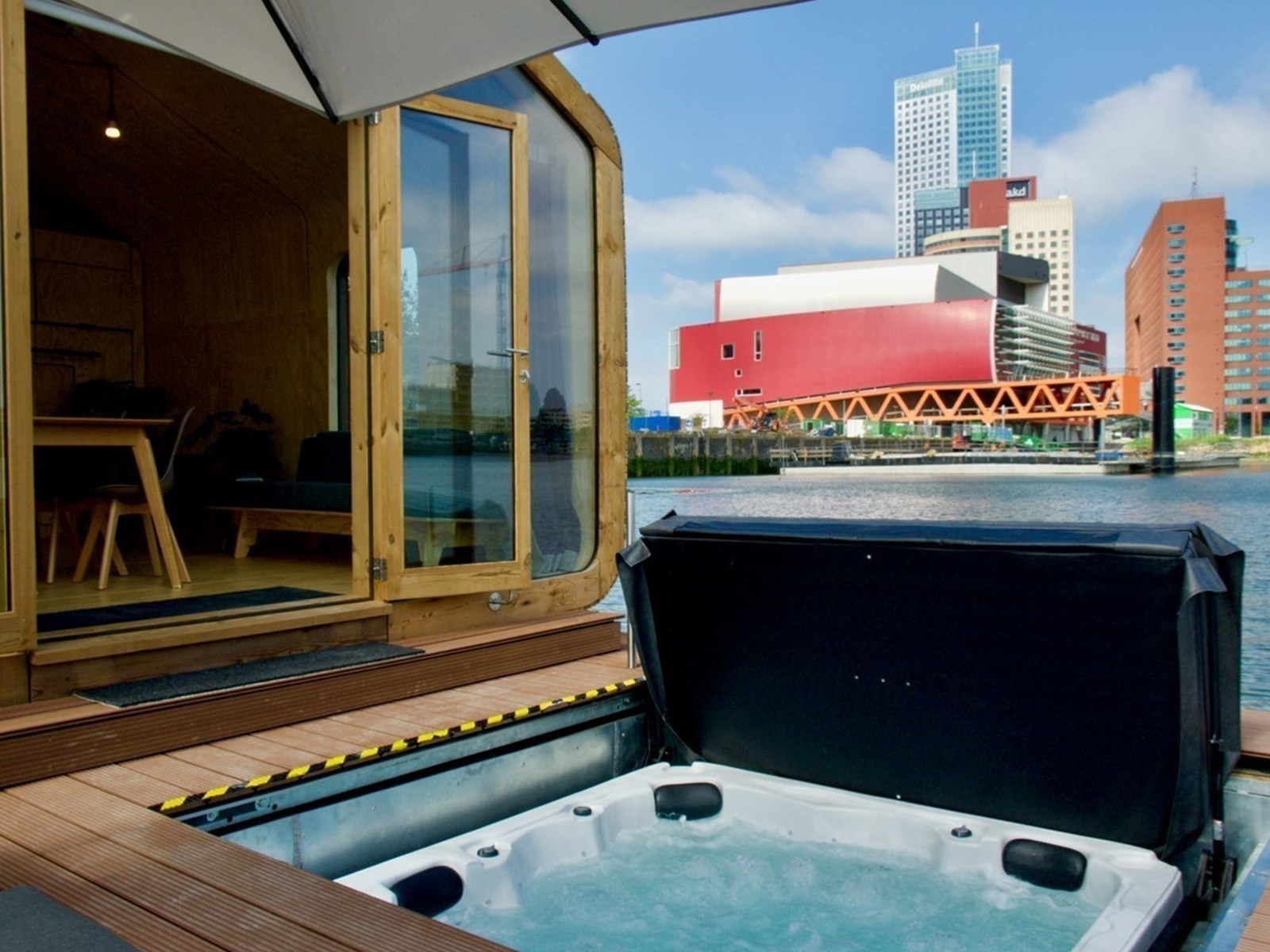 Bubbelen in de privéjacuzzi van je Tiny house op het water met uitzicht op de haven van Rotterdam